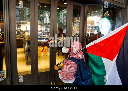 Melbourne, Australien. April 2025. Während einer pro-palästinensischen Kundgebung in Melbourne ruft ein Demonstrant vor einem Starbucks-Café Slogans. Demonstranten versammelten sich in Melbourne zu einer wöchentlichen pro-palästinensischen Kundgebung, um einen sofortigen Waffenstillstand in Gaza zu fordern und den internationalen Druck zur Beendigung des Konflikts zu erhöhen. Die Demonstration kommt, da die Zahl der Todesopfer in Gaza 33.000 übersteigt, aufgrund der laufenden israelischen Militäroperationen. (Foto: YE Myo Khant/SOPA Images/SIPA USA) Credit: SIPA USA/Alamy Live News Stockfoto