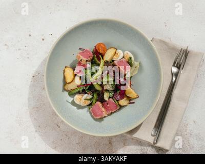 Thunfischsalat nach asiatischer Art mit Salat, Eiern, Kirschtomaten, Kartoffeln und Thunfischstücken in Sesamsamen. Gesundes Abendessen. Kopierbereich. Draufsicht oder flache Lagen Stockfoto