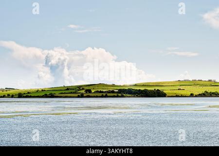 Ruhige Gewässer erstrecken sich über Inchydoney Island in Irland und bezaubern Besucher mit ihren lebhaften Grün- und Blautönen. Der weitläufige Himmel ist mit unterbrochen Stockfoto