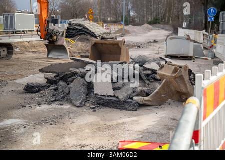 Gebrochene Asphaltteile und Baggerlöffel auf einer Straßenbaustelle Stockfoto