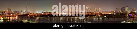 Panoramablick auf die beleuchtete Skyline von Dubai bei Nacht, mit dem berühmten Burj Khalifa, der sich im ruhigen Wasser spiegelt und die Stadt Stockfoto