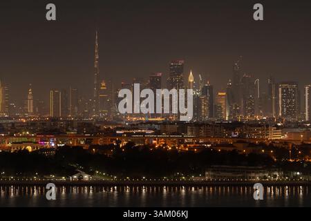 Beleuchtete Wolkenkratzer von Dubais Skyline bei Nacht, mit dem berühmten Burj Khalifa, schaffen ein fesselndes Stadtpanorama, das sich im ruhigen Wasser spiegelt Stockfoto
