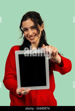 Lächelnde junge Frau, die ein digitales Tablet mit leerem Bildschirm zeigt und für die App oder Website wirbt Stockfoto