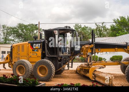 Mann fährt gelben Cat-Motorgrader für den Straßenbau in Smithville, Texas, USA Stockfoto