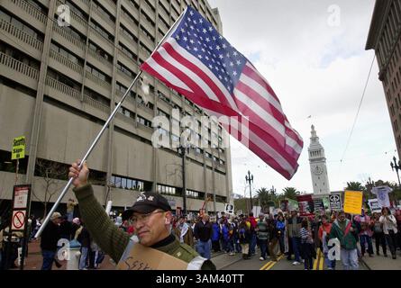 16. Februar 2003 - USA - KRT US-NACHRICHTENGESCHICHTE SCHLEPPTE: USIRAQ-DEMOS KRT FOTO VON JOSE CARLOS FAJARDO/CONTRA COSTA TIMES (16. Februar) SAN FRANCISCO, CA -- Modesto Fernandez aus Berkeley trägt eine US-Flagge, während er am Sonntag, 16. Februar 2003 die Market Street in San Francisco, Kalifornien, durchmarschiert. Tausende Demonstranten gegen den Krieg marschierten zum Civic Center, um gegen den möglichen Krieg gegen den Irak zu protestieren. (nk) 2003 (Bild: © Jose Carlos Fajardo/mct/ZUMAPRESS.com) Stockfoto