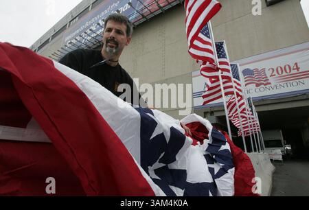 24. Juli 2004 - USA - KEINE MAGIE, KEINE VERKÄUFE -- KRT US NEWS STORY SCHLEPPTE: CVN-DEMOCRATS KRT FOTO VON RICHARD MICHAEL PRUITT/DALLAS MORNING NEWS (24. Juli) BOSTON, MA - David Forshee, ein Arbeiter im Mystic Scenic Studio von Boston, deckt Fahnen über eine Betonbarriere, Samstag, 24. Juli 2004, im Fleet Center, dem Ort der Demokratischen Nationalkonvention, die am Montag beginnt. (smd) 2004 (Kreditbild: © Dallas Morning News/mct/ZUMAPRESS.com) Stockfoto