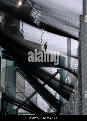 24. Juli 2004 - USA - KRT US-NEWS STORY SCHLEPPTE: CVN-DEMOCRATS KRT FOTO VON CHUCK KENNEDY/KRT (24. Juli) BOSTON, MA - wie durch den Eindämmungszaun in der Protestzone für die Demokratische Nationalkonvention gesehen, steht am Samstag, den 24. Juli 2004 ein Wachmann in der Nähe des Fleet Center in Boston, Massachusetts. (smd) 2004 (Abbildung: © PHOTOGNOSOURCE/mct/ZUMAPRESS.com) Stockfoto