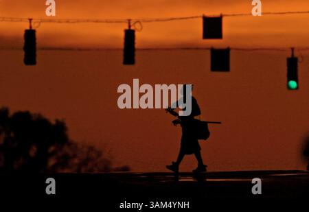 22. SEPTEMBER 2004 - USA - KEINE MAGIE, KEINE VERKÄUFE -- KRT STAND ALONE US NEWS FOTO SCHLEPPTE: WEA-HERBST KRT FOTO VON KARL MERTON FERRON/BALTIMORE SUN (WASHINGTON, DC OUT) (22. SEPTEMBER) BALTIMORE, MD -- Reginald Alston, 19 Jahre alt, aus Baltimore, Maryland, überquert die 25th Street in Baltimore mit seinen Lacrosse-Sticks in der Hand und macht sich vom dreiwöchentlichen Training mit dem Hopkins Club auf den Weg, während das Licht der untergehenden Sonne den westlichen Himmel am ersten Herbstmittwochs, den 22. September 2004, in Herbstfarben umhüllt. (nk) 2004 (Bild: © Karl Merton Ferron/mct/ZUMAPRESS.com) Stockfoto