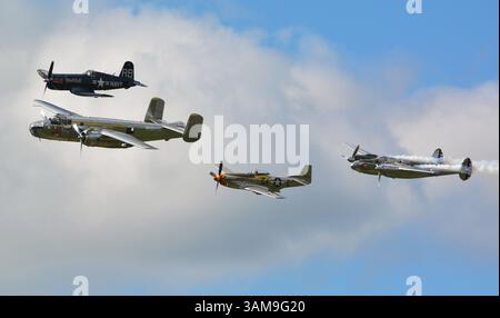 Eine Formation von vier kolbengetriebenen Warbirds, mit dem P-38-Rauch, über dem Sywell-Flugplatz, Großbritannien Stockfoto