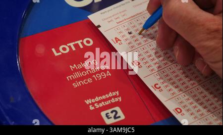 Ein Spieler der Nationallotterie in Großbritannien wählt die Zahlen für sein Lottoticket aus. Stockfoto