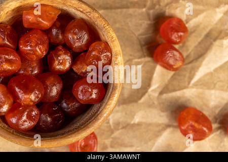 Kandiertes Kumquat, gekocht mit Zuckersirup kandierte Früchte von kleinen Früchten des Kumquats, getrocknete Früchte sind auf Papier in der Nähe verstreut Stockfoto