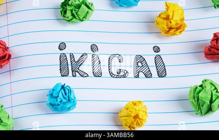 Das Wort Ikigai steht auf einem Notizblock mit bunten zerknitterten Papierkugeln. IKIGAI ist ein japanisches Konzept. Stockfoto