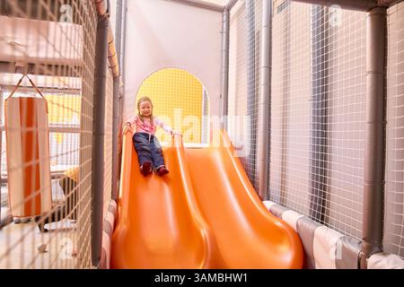 Dieses helle und verspielte Bild zeigt die Begeisterung eines Kindes in einer sicheren, stimulierenden Umgebung, perfekt für die Darstellung von Kindertagesstätten, Familienspaß oder Chi Stockfoto