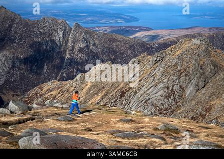 Junge Frau Bergwandererin direkt unterhalb des Gipfels von Goatfell auf der Isle of Arran, North Ayrshire, Schottland, Großbritannien. Stockfoto