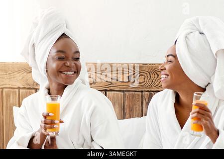 Glückliche schwarze Freundinnen beim Frühstück im Bett Stockfoto