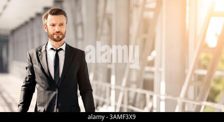 Wohlhabender Geschäftsmann mit Gepäck, der am Flughafen vorbei läuft Stockfoto