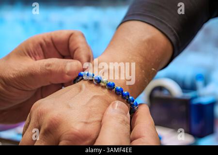 Ein Juwelier trägt ein maßgeschneidertes Lapislazuli- und Silberarmband auf den Arm eines männlichen Kunden auf dem Großen Basar in Istanbul, Türkei Stockfoto