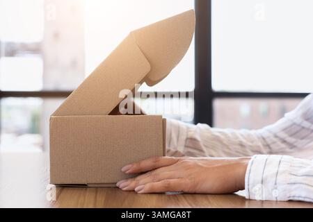 Frau öffnet Box mit neuem Paket, Nahaufnahme Stockfoto