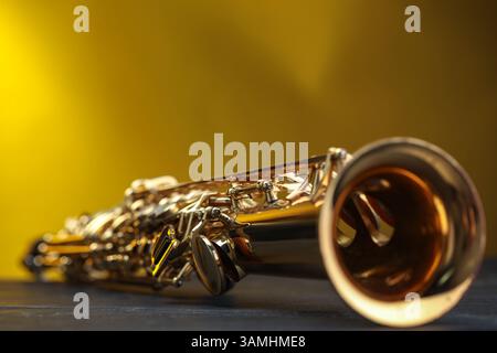 Jazz. Ein schönes Saxophon auf schwarzem Tisch vor farbigem Hintergrund, Nahaufnahme Stockfoto
