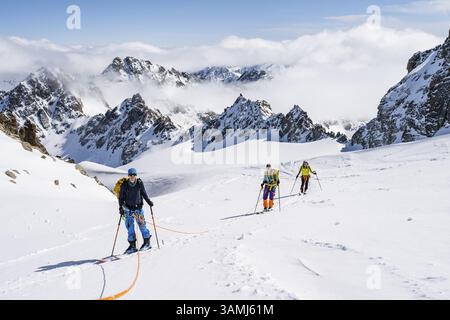 Skitourer mit Seil, Seilteam auf dem Gletscher Vadret da Porchabella beim Aufstieg zum Gipfel des Piz Kesch, Berglandschaft im Winter, alpines To Stockfoto