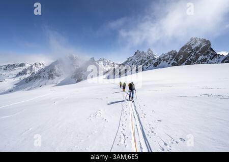 Skitourer mit Seil, Seilteam auf dem Gletscher Vadret da Porchabella beim Aufstieg zum Gipfel des Piz Kesch, Berglandschaft im Winter, alpines To Stockfoto