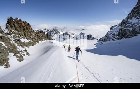Skitourer mit Seil, Seilteam auf dem Gletscher Vadret da Porchabella beim Aufstieg zum Gipfel des Piz Kesch, Berglandschaft im Winter, alpines To Stockfoto