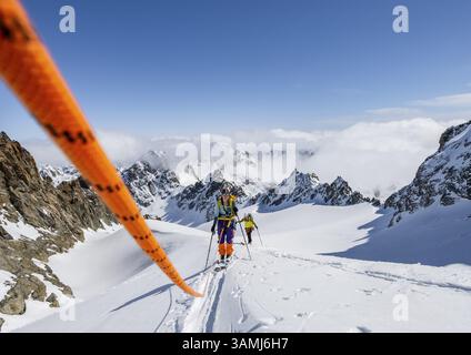 Skitourer mit Seil, Seilteam auf dem Gletscher Vadret da Porchabella beim Aufstieg zum Gipfel des Piz Kesch, Berglandschaft im Winter, alpines To Stockfoto