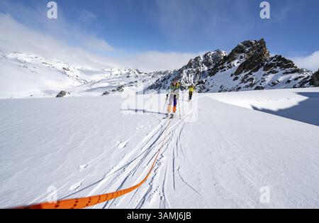 Skitourer mit Seil, Seilteam auf dem Gletscher Vadret da Porchabella beim Aufstieg zum Gipfel des Piz Kesch, Berglandschaft im Winter, alpines To Stockfoto