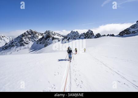 Skitourer mit Seil, Seilteam auf dem Gletscher Vadret da Porchabella beim Aufstieg zum Gipfel des Piz Kesch, Berglandschaft im Winter, alpines To Stockfoto
