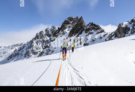 Skitourer mit Seil, Seilteam auf dem Gletscher Vadret da Porchabella beim Aufstieg zum Gipfel des Piz Kesch, Berglandschaft im Winter, alpines To Stockfoto