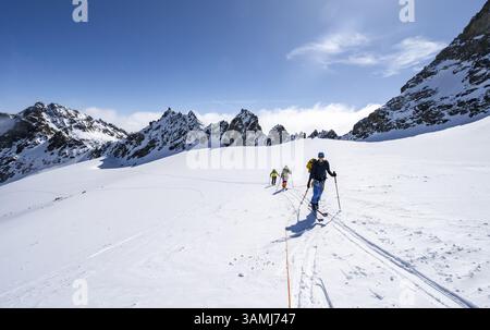 Skitourer mit Seil, Seilteam auf dem Gletscher Vadret da Porchabella beim Aufstieg zum Gipfel des Piz Kesch, Berglandschaft im Winter, alpines To Stockfoto
