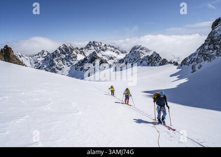 Skitourer mit Seil, Seilteam auf dem Gletscher Vadret da Porchabella beim Aufstieg zum Gipfel des Piz Kesch, Berglandschaft im Winter, alpines To Stockfoto