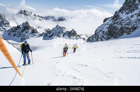 Skitourer mit Seil, Seilteam auf dem Gletscher Vadret da Porchabella beim Aufstieg zum Gipfel des Piz Kesch, Berglandschaft im Winter, alpines To Stockfoto