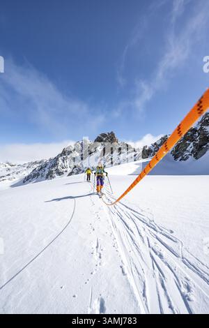 Skitourer mit Seil, Seilteam auf dem Gletscher Vadret da Porchabella beim Aufstieg zum Gipfel des Piz Kesch, Berglandschaft im Winter, alpines To Stockfoto