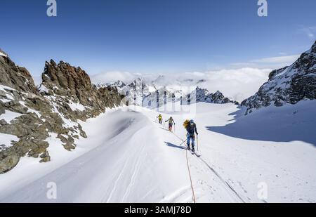 Skitourer mit Seil, Seilteam auf dem Gletscher Vadret da Porchabella beim Aufstieg zum Gipfel des Piz Kesch, Berglandschaft im Winter, alpines To Stockfoto