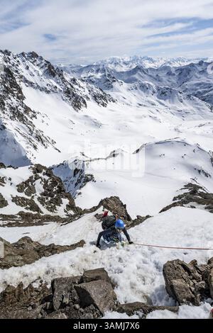 Bergsteiger klettern an einem steilen, mit einem Seil gesicherten Schneehang, im Winter Aufstieg zum Gipfel des Piz Grialetsch, Blick auf das Bergpanorama mit Schnee, Stockfoto