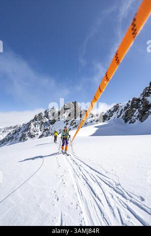 Skitourer mit Seil, Seilteam auf dem Gletscher Vadret da Porchabella beim Aufstieg zum Gipfel des Piz Kesch, Berglandschaft im Winter, alpines To Stockfoto