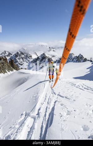 Skitourer mit Seil, Seilteam auf dem Gletscher Vadret da Porchabella beim Aufstieg zum Gipfel des Piz Kesch, Berglandschaft im Winter, alpines To Stockfoto