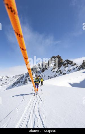 Skitourer mit Seil, Seilteam auf dem Gletscher Vadret da Porchabella beim Aufstieg zum Gipfel des Piz Kesch, Berglandschaft im Winter, alpines To Stockfoto