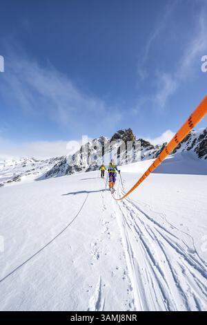 Skitourer mit Seil, Seilteam auf dem Gletscher Vadret da Porchabella beim Aufstieg zum Gipfel des Piz Kesch, Berglandschaft im Winter, alpines To Stockfoto