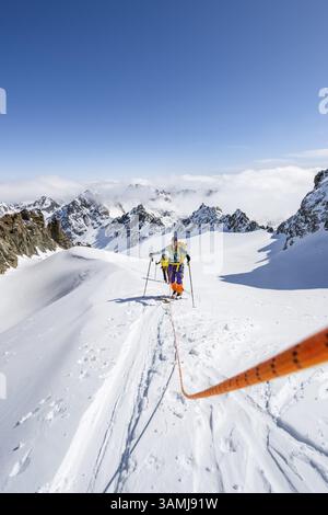 Skitourer mit Seil, Seilteam auf dem Gletscher Vadret da Porchabella beim Aufstieg zum Gipfel des Piz Kesch, Berglandschaft im Winter, alpines To Stockfoto