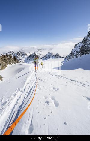 Skitourer mit Seil, Seilteam auf dem Gletscher Vadret da Porchabella beim Aufstieg zum Gipfel des Piz Kesch, Berglandschaft im Winter, alpines To Stockfoto