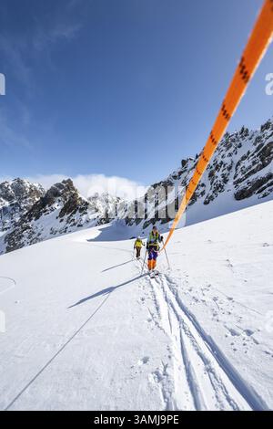 Skitourer mit Seil, Seilteam auf dem Gletscher Vadret da Porchabella beim Aufstieg zum Gipfel des Piz Kesch, Berglandschaft im Winter, alpines To Stockfoto