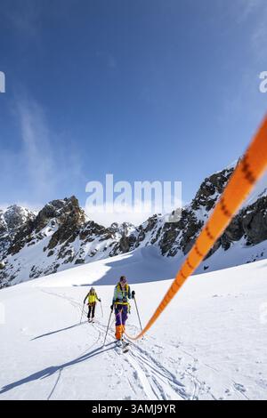 Skitourer mit Seil, Seilteam auf dem Gletscher Vadret da Porchabella beim Aufstieg zum Gipfel des Piz Kesch, Berglandschaft im Winter, alpines To Stockfoto