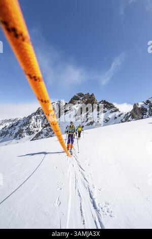 Skitourer mit Seil, Seilteam auf dem Gletscher Vadret da Porchabella beim Aufstieg zum Gipfel des Piz Kesch, Berglandschaft im Winter, alpines To Stockfoto