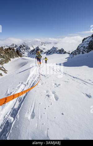 Skitourer mit Seil, Seilteam auf dem Gletscher Vadret da Porchabella beim Aufstieg zum Gipfel des Piz Kesch, Berglandschaft im Winter, alpines To Stockfoto