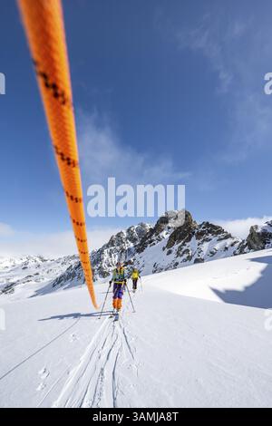 Skitourer mit Seil, Seilteam auf dem Gletscher Vadret da Porchabella beim Aufstieg zum Gipfel des Piz Kesch, Berglandschaft im Winter, alpines To Stockfoto