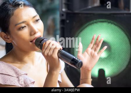 Die junge Frau singt ins Mikrofon Stockfoto