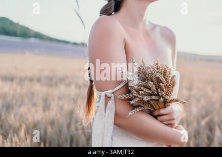 Frau, die Weizen auf einem Feld hält Stockfoto