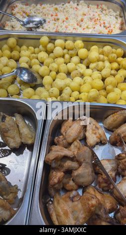 Gekochte Hähnchenflügel, gekochte Kartoffeln und Reis mit Gemüse in Metallbehältern, servierfertig Stockfoto